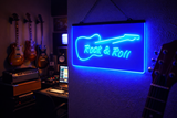 Neon sign with 'Rock & Roll' and guitar design in a music-themed room.