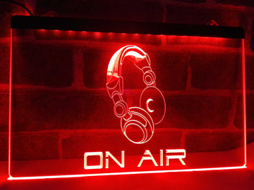 Red On Air LED sign with an engraved headphone graphic lit against a brick wall